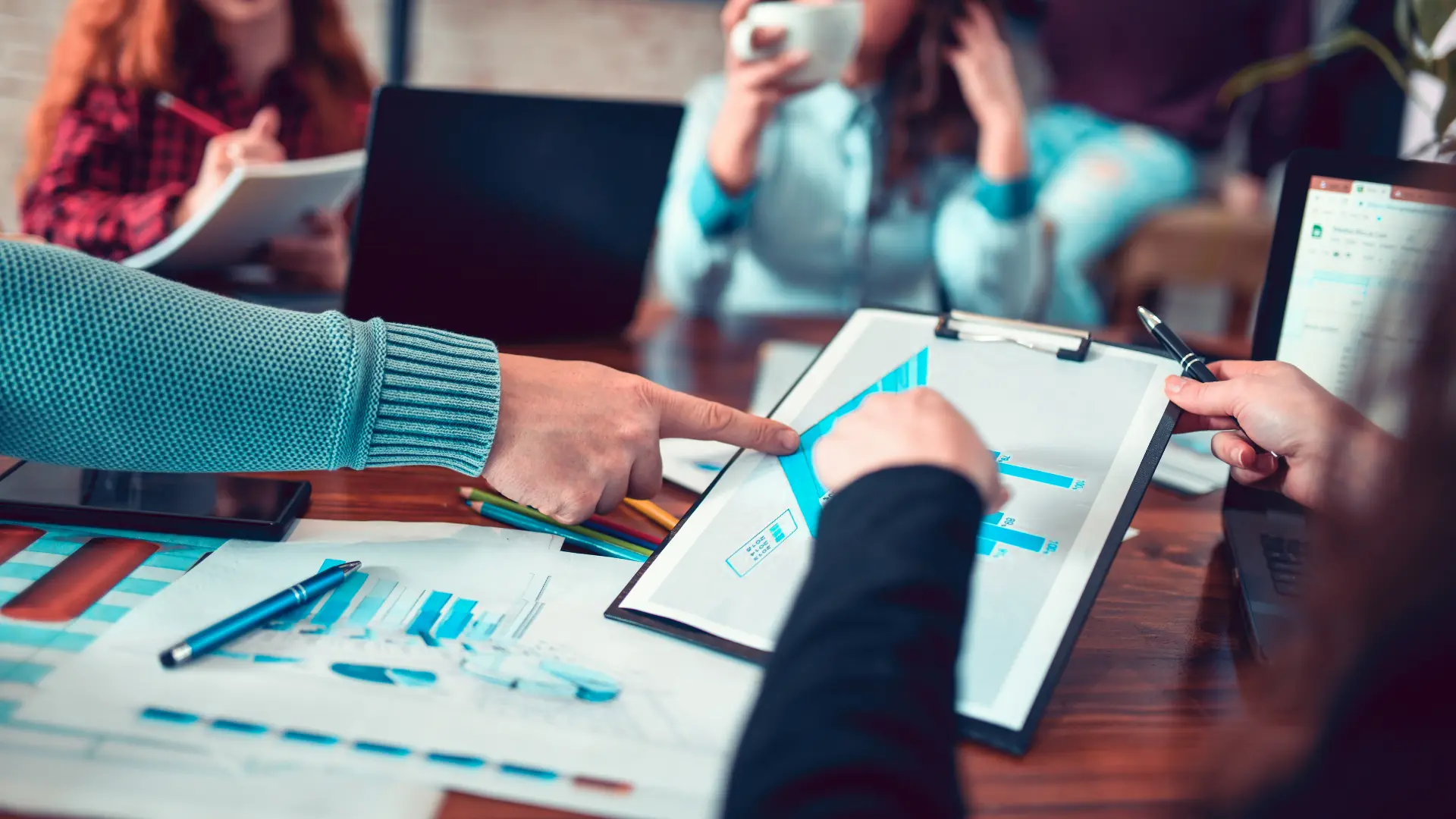 Team comparing bar chart reports on a clipboard and printouts during an ERP evaluation meeting